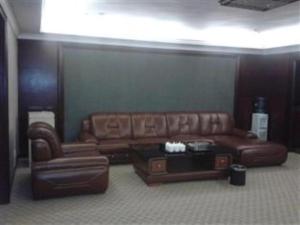 uma sala de estar com um sofá de couro e uma mesa de centro em Guangna Hotel em Huizhou