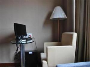 uma sala de estar com uma mesa com um computador portátil e uma cadeira em Guangna Hotel em Huizhou