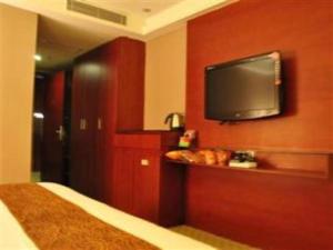 Guangna Hotel في هويزو: غرفة نوم مع تلفزيون بشاشة مسطحة على جدار احمر