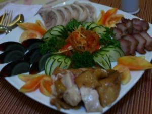einen Teller mit Gemüse und Fleisch auf dem Tisch in der Unterkunft Hotel Ariana in Lossoc