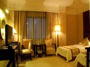 a hotel room with a bedroom with a bed and chairs at Quanzhou Royal Prince Hotel in Quanzhou