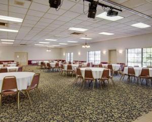 um salão de banquetes com mesas e cadeiras brancas em Econo Lodge Conference Center em El Dorado