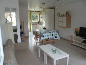 a living room with a table and a kitchen at Les Carcahutes in Audresselles