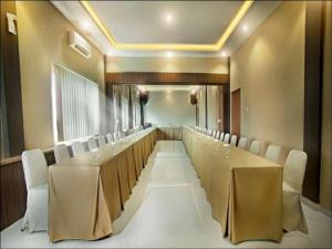 Benteng Hotel Pekanbaru في Parit: قاعة اجتماعات مع طاولة طويلة وكراسي بيضاء
