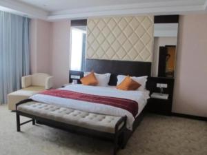 a large bedroom with a large bed and a chair at Aksu Pudong Holiday Hotel in Aksu