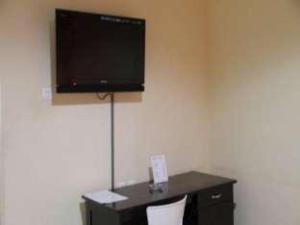a room with a desk with a television on a wall at Lotus Hotel in Parepare
