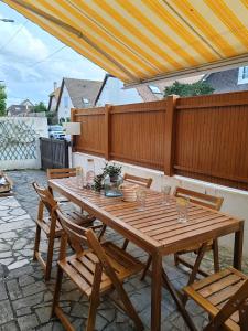 une table et des chaises en bois sur une terrasse dans l'établissement Villa Francette à 500m de la plage, à Ouistreham