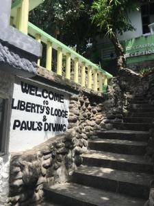un escalier en pierre avec un panneau sur le côté du bâtiment dans l'établissement Liberty's Community Lodge and Diving, à Dumaguete