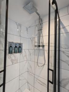 a bathroom with a shower with white marble tiles at Blue Horizon Holiday Cottage - 4 Minute Walk to the Beach in Weymouth