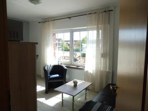 ein Wohnzimmer mit einem Sofa, einem Tisch und einem Fenster in der Unterkunft Ferienanlage Blinkfuer in Dornumersiel