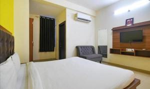 1 dormitorio con 1 cama, TV y silla en Hotel Shubhshree, en Indore