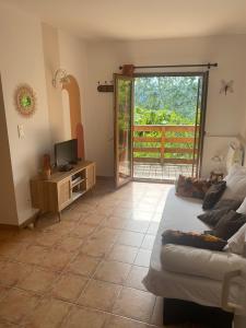 a living room with a bed and a tv and a balcony at Le Mas des Eglantiers in Propiac