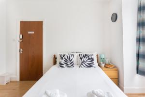 - une chambre avec un lit doté de draps blancs et d'une porte en bois dans l'établissement Wood Green Budget Rooms - Next to Mall & Metro Station - 10 Min to City Center, à Londres