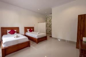 2 Betten in einem Zimmer mit weißen Wänden und roten Kissen in der Unterkunft Omah Nusa Villa RedPartner in Nusa Penida