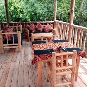 drewniany taras ze stołem i krzesłami w obiekcie Murchison Giraffe Camp w mieście Murchison Falls National Park
