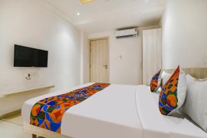 a bedroom with a white bed with a colorful blanket at FabHotel Blue Ocean in Indore