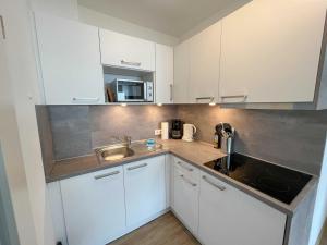 a kitchen with white cabinets and a sink at Appartementhaus Nige Ooge Wohnung Nr 1 in Sahlenburg