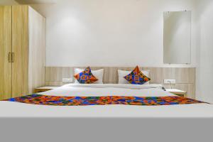 a bedroom with a large white bed with colorful pillows at FabHotel Blue Ocean in Indore +21 photos
