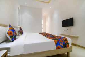 a bedroom with a white bed and a tv on a wall at FabHotel Blue Ocean in Indore