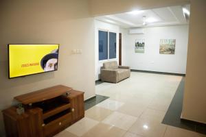een woonkamer met een bank en een tv aan de muur bij The Rubicon Cozy Studio Room 2 in Accra