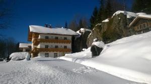 um edifício coberto de neve em frente a uma casa em Pension Haus Sonnenfels em Bodenmais