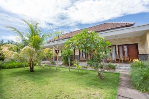 une maison avec des palmiers devant elle dans l'établissement Omah Nusa Villa RedPartner, à Nusa Penida