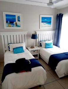 a bedroom with two beds and a table with a lamp at Indigo Bay 29 in Margate