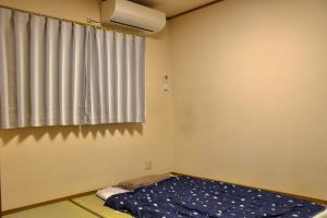 a small room with a bed and a window at Niji Homestay in Osaka