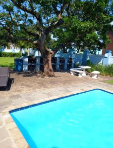 uma piscina azul com uma árvore num quintal em Indigo Bay 29 em Margate