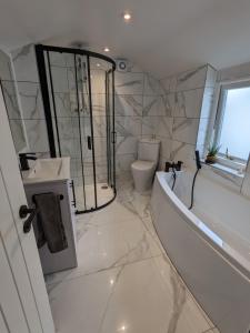 a white bathroom with a tub and a toilet at Blue Horizon Holiday Cottage - 4 Minute Walk to the Beach in Weymouth