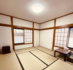 an empty room with a table and windows at Urasa Cottage @ Snow Countryside in Minami Uonuma