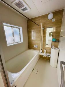 un bagno con ampia vasca e finestra di Urasa Cottage @ Snow Countryside a Minami Uonuma