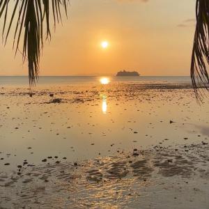 una puesta de sol en la playa con una isla a lo lejos en Boon Heritage House Koh Samui, en Koh Samui 