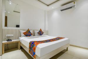 a white bedroom with a bed and a mirror at FabHotel Blue Ocean in Indore