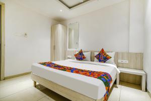 a white bedroom with a large bed with colorful pillows at FabHotel Blue Ocean in Indore