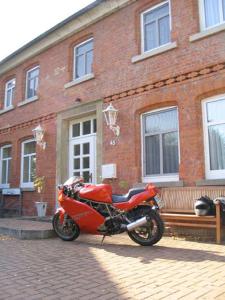 una motocicleta roja estacionada frente a un edificio de ladrillo en Weserlounge Apartments, en Hessisch Oldendorf