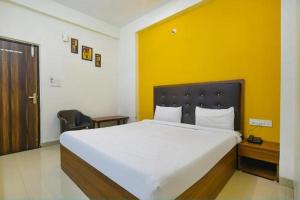 um quarto com uma cama grande e uma parede amarela em Hotel Shubhshree em Indore