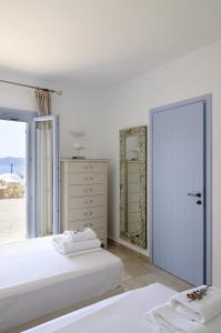 a white bedroom with two beds and a mirror at Villa St' Astra in Koufonisia