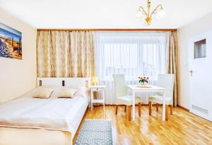 a bedroom with a bed and a table with chairs at Willa Muszelka Przy Morzu in Jastarnia