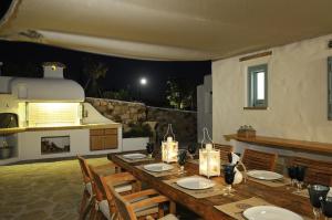 a long wooden table with chairs and a kitchen at Villa St' Astra in Koufonisia