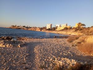 a beach with rocks and buildings in the background at Casa Alkabir Campello in El Campello