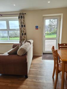 uma sala de estar com um sofá, uma mesa e janelas em Holiday Cottage 4 em Penrith