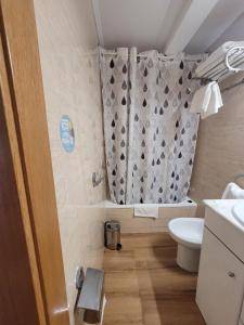 y baño con cortina de ducha y aseo. en Hostal San Felix en Gijón