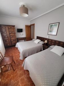 Habitación de hotel con 3 camas y TV en Hostal San Felix en Gijón