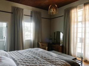 a bedroom with a bed and a desk and windows at Kokerboom House in Vanrhynsdorp