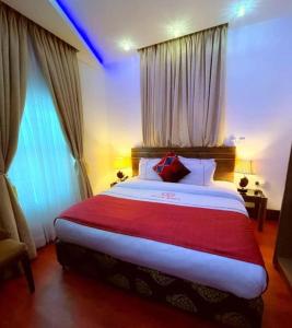 a bedroom with a large bed with a red blanket at Proof Hotel Lekki in Lagos
