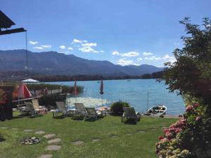 a group of chairs sitting on the grass near the water at Ferienwohnungen Mistelbauer DIREKT am Faaker See in Egg am Faaker See