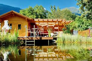 a log cabin with a deck over a body of water at Haus Wallner in Dellach im Drautal