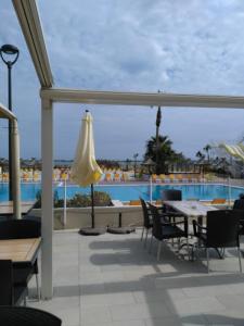 een patio met een tafel en stoelen en een zwembad bij Mobil-home Clim, Tv, Lv - Camping Lac des Rêves 4 étoiles - 010 in Lattes