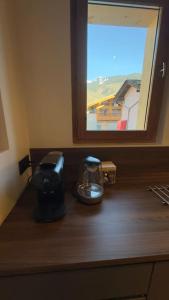 eine Küchentheke mit einer Kaffeemaschine und einem Fenster in der Unterkunft Maisonnette à Courchevel. in Courchevel
